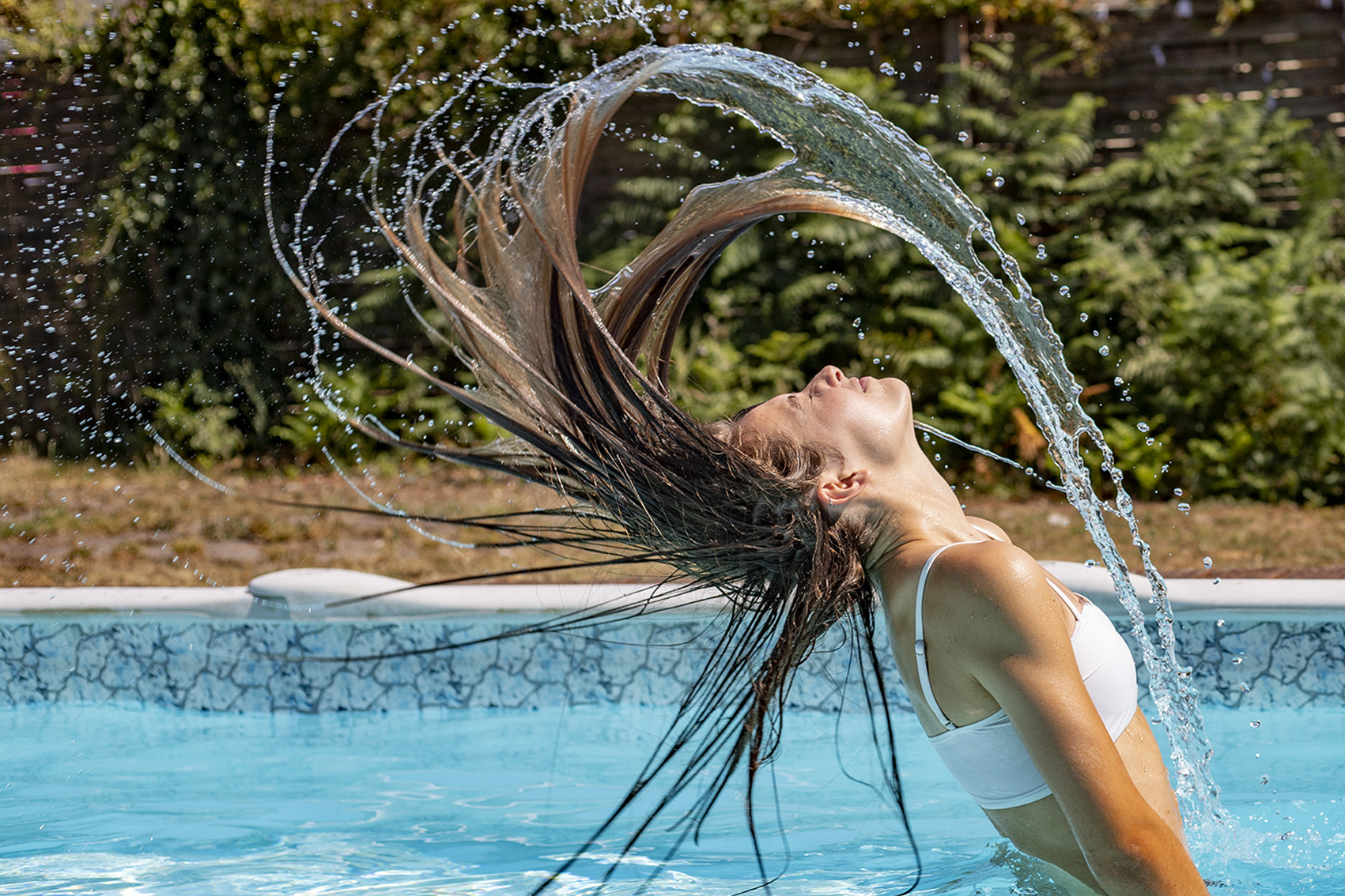 femme dans la piscine avec les cheveux longs pour une photo avec effet d'eau