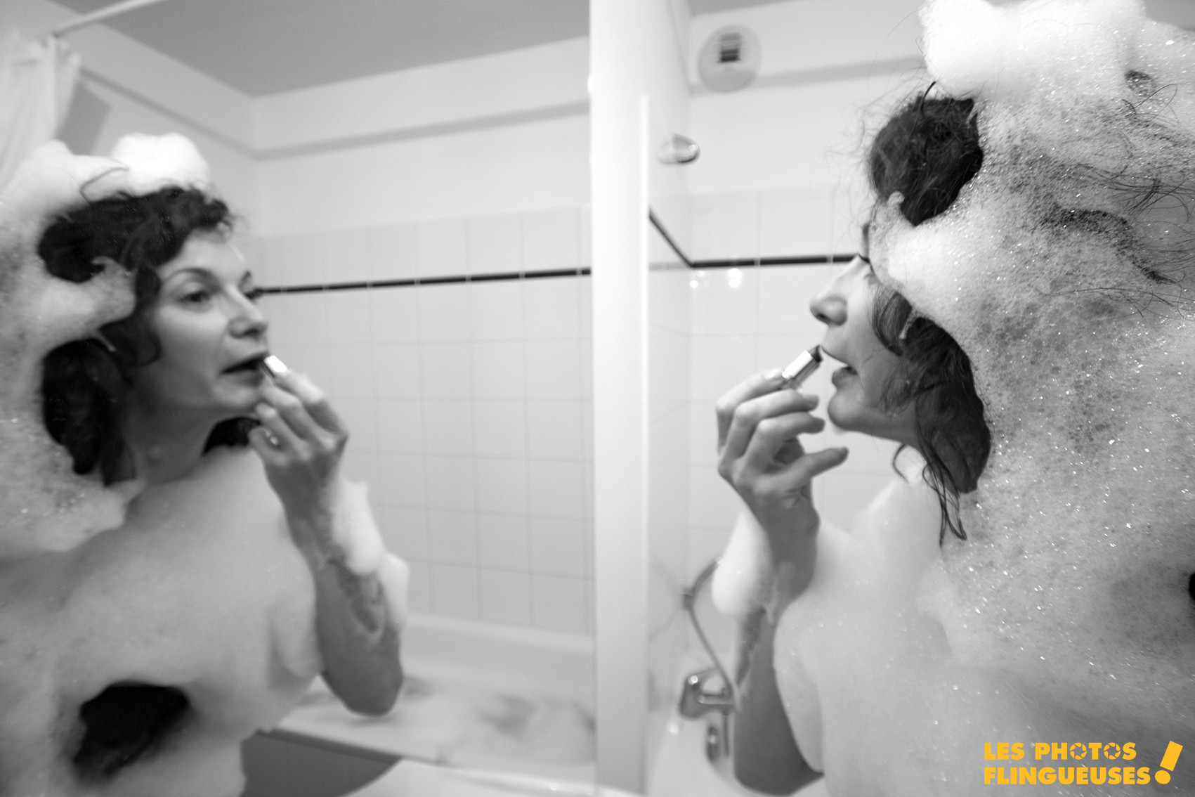 photo en noir et blanc d'une femme qui sort de la douche avec de la mousse sur le corps et le visage et qui se maquille sur une photo originales